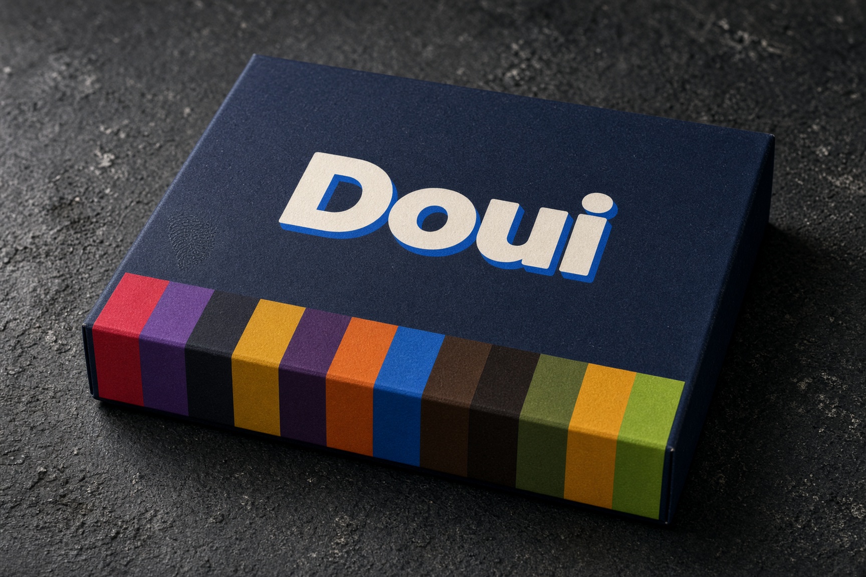 La caja de doce de Doui, cerrada, con el logotipo en la tapa y la tira de doce colores doblando por el canto
